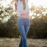 woman wearing white crop top and blue denim jeans walking on green grass at daytime